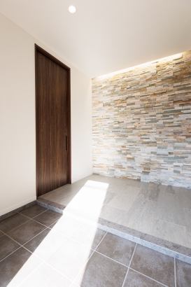高級感のあるタイル張りの壁面と間接照明が迎えてくれる玄関。